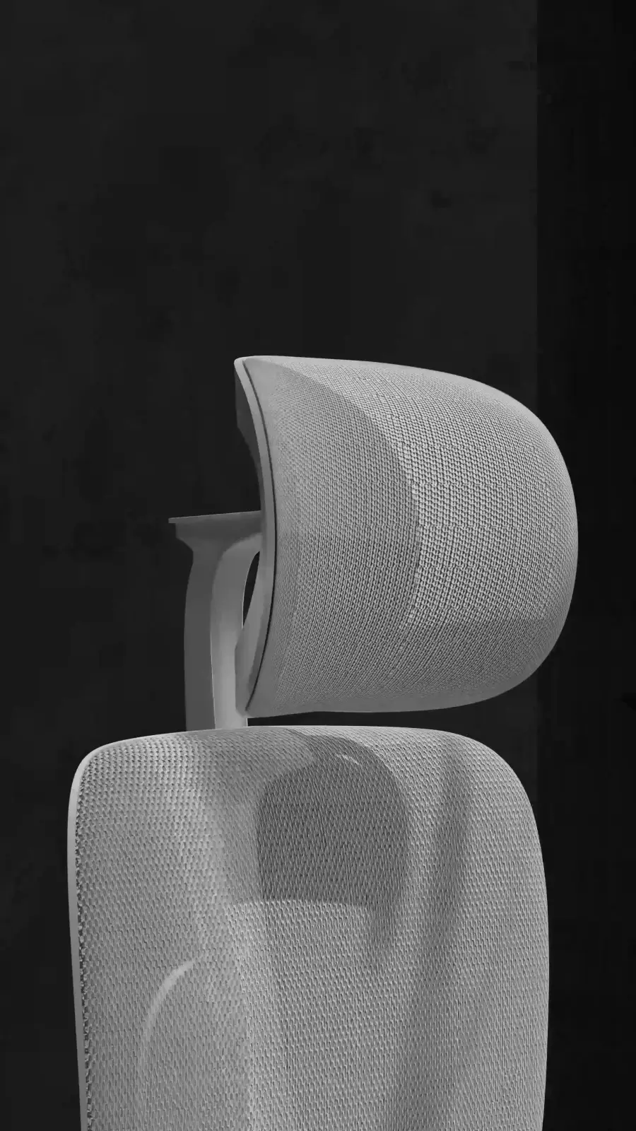 Close-up of the grey chair's mesh headrest and back in a dark room, a frame from Bosq's 3D product film