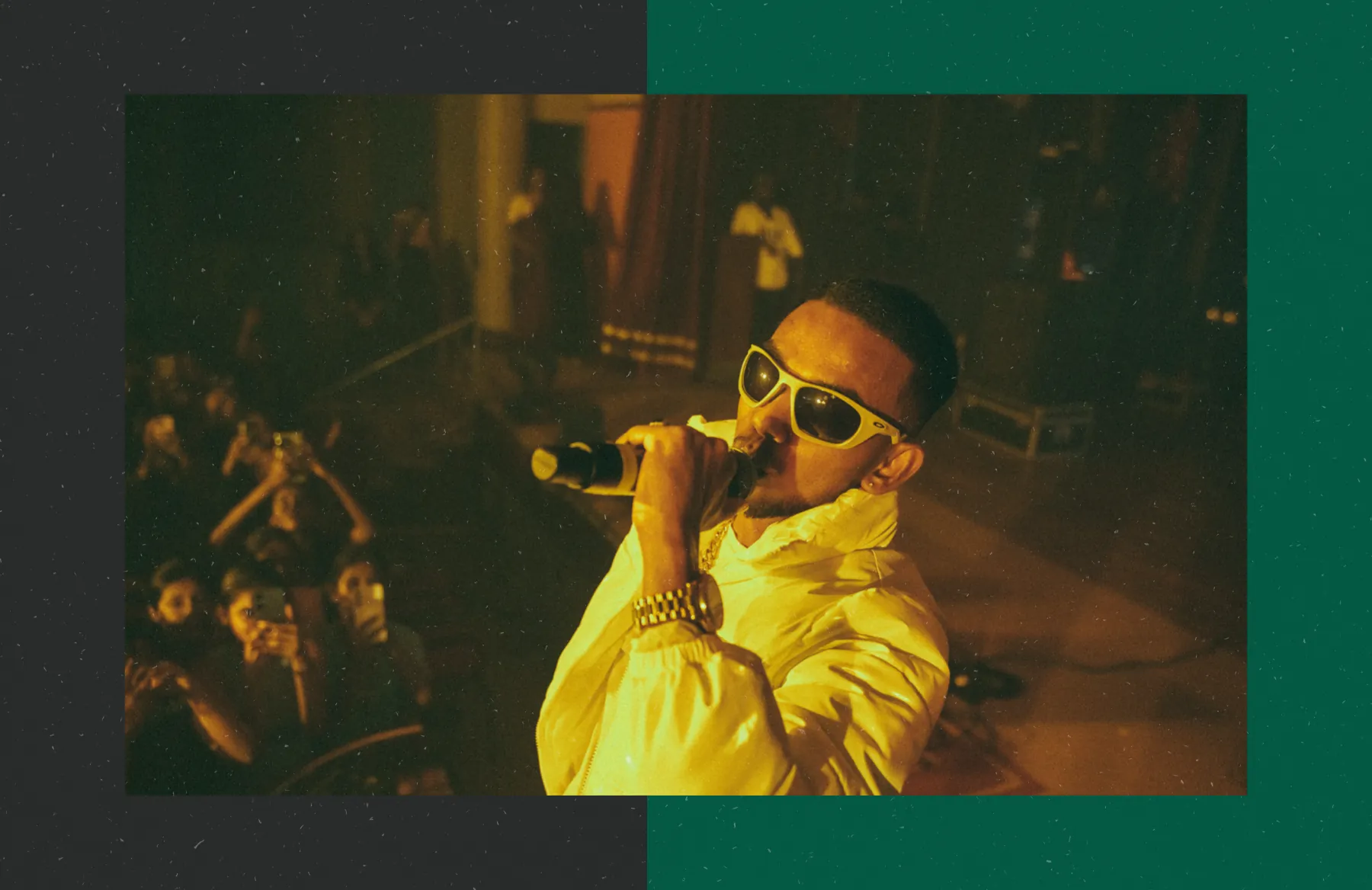 A warm, gold-toned stage shot, framed across a split ground of charcoal and green.