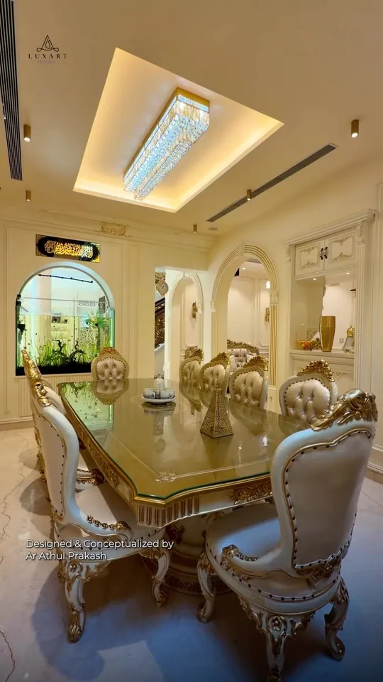 A formal dining room with carved cream chairs under a crystal chandelier, on the cover of a Luxart Builders reel