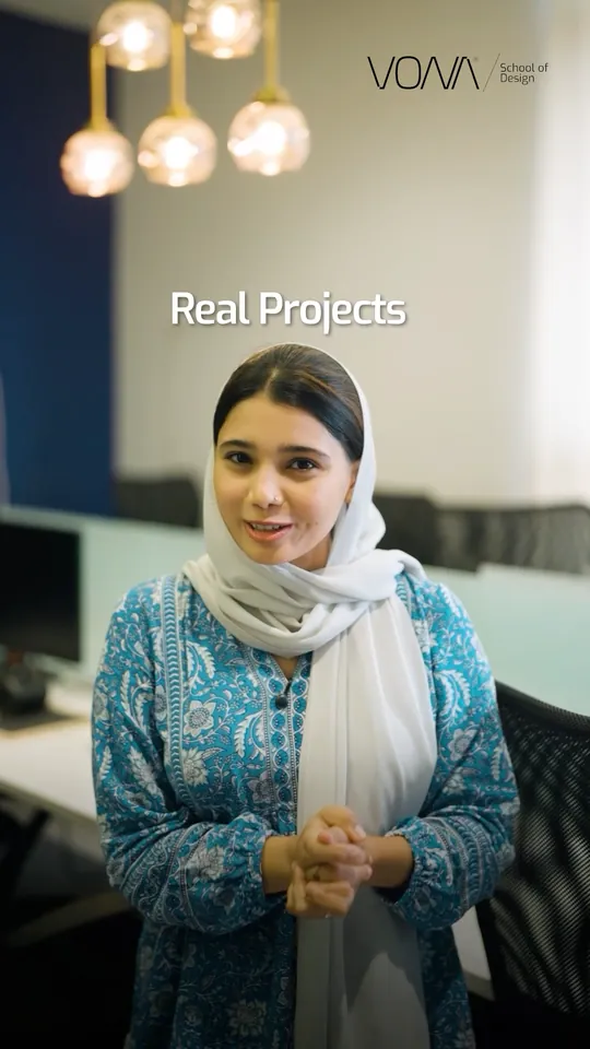 Presenter in a blue printed kurta and white scarf under pendant lights, with the words Real Projects on screen, in a VONA School of Design Meta ad